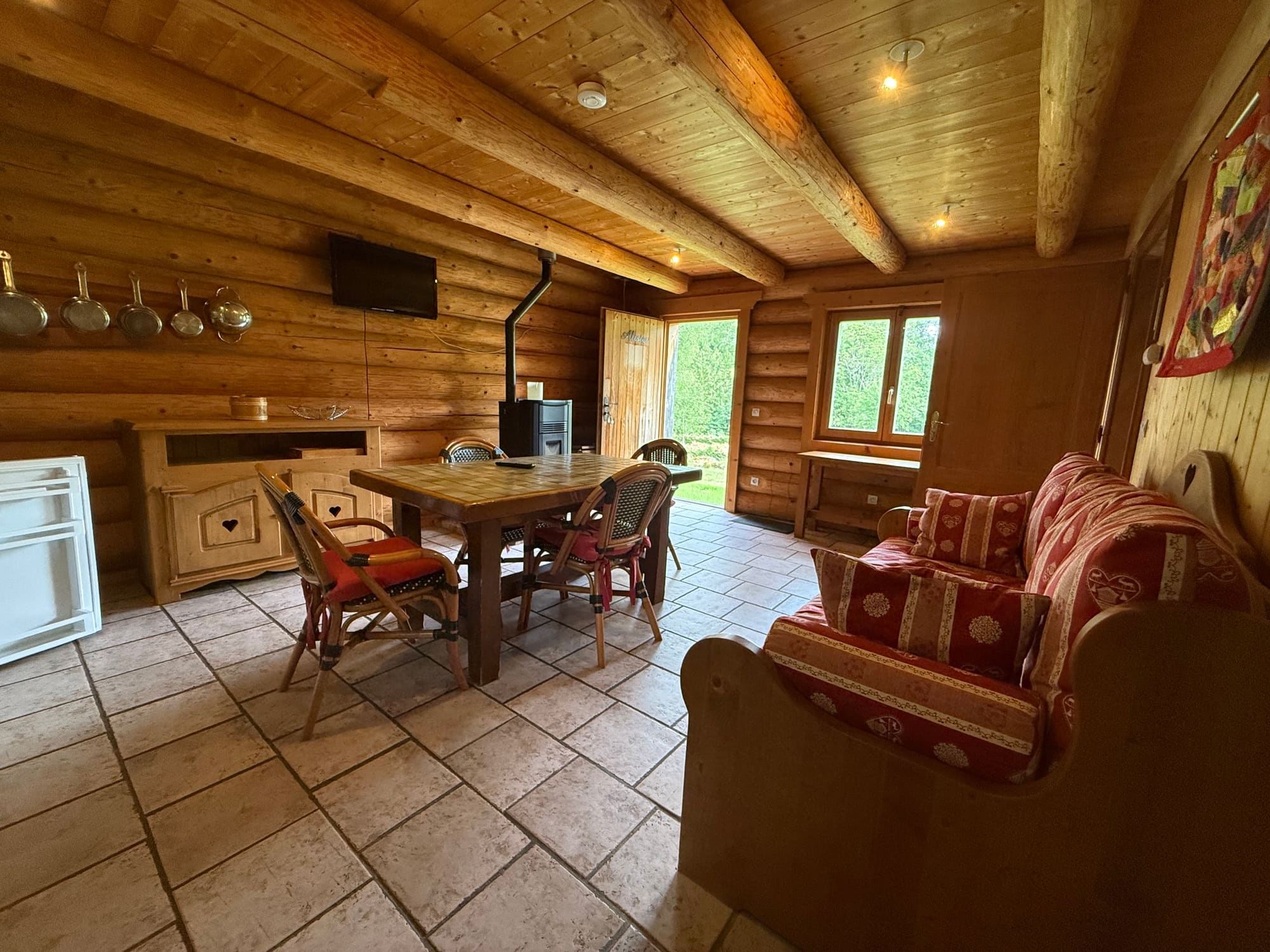 Le séjour, sa banquette et son poêle, ouvert sur la terrasse